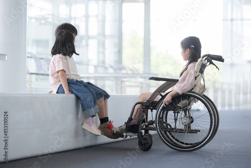 車椅子にのる小学生と目線を一緒に話す友達 心のバリアフリーのイメージ 顔無し