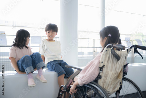 車椅子にのる小学生と目線を一緒に話す友達 心のバリアフリーのイメージ