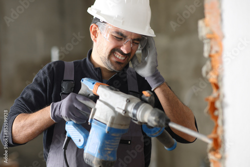 Cosntruction worker suffering head ache working with noisy tool