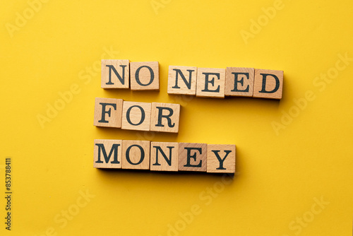 a yellow warm background without shadows wooden cubes with black letters laid out word no need for money