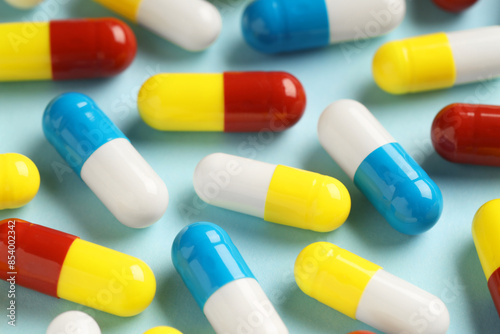 Many antibiotic pills on light blue background, closeup