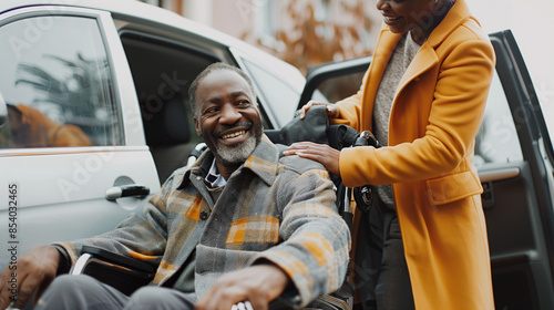 Nurse is helping a senior african american man in a wheelchair getting out of a car on a sunny autumn day