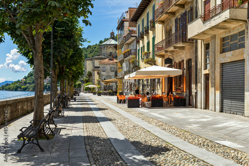 Narrow cobblestone street and along outdoor restaurants in old town of Cannobio, Italy.