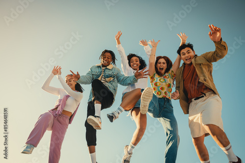 Group of friends jumping and having fun outdoors in the sunshine