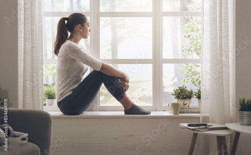 Woman sitting next to a window and looking away