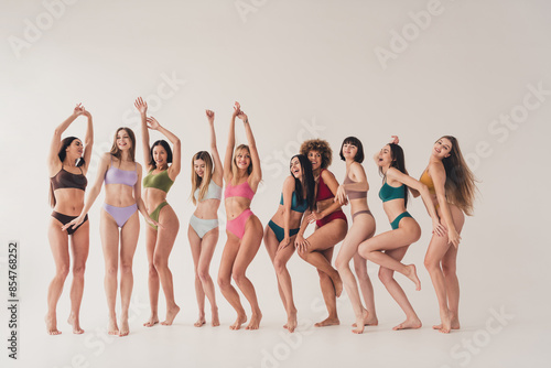 Full length photo of barefoot laughing funky girls in lingerie teasing and tempting at white studio background