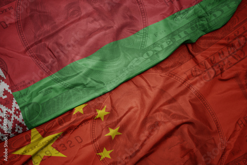 waving colorful flag of belarus and national flag of china on the dollar money background. finance concept.