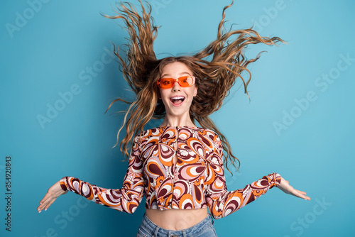 Photo of nice young girl throw hair wear top isolated on blue color background