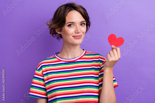Portrait of cute friendly girl hand hold small red paper heart symbol isolated on purple color background