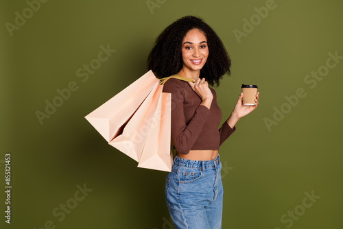 Photo portrait of pretty young girl shopping bags drink coffee wear trendy brown outfit isolated on khaki color background
