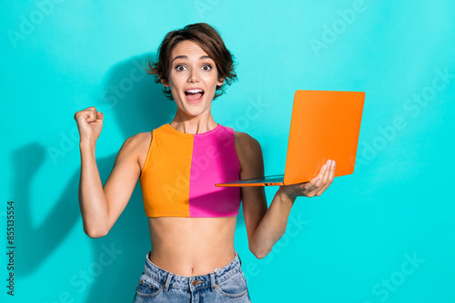 Photo of impressed lucky lady dressed colorful top winning game modern device empty space isolated turquoise color background
