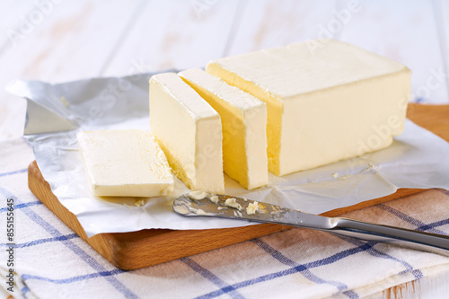 cut block butter on a white wooden table, selective focus. Stick of butter, cut.