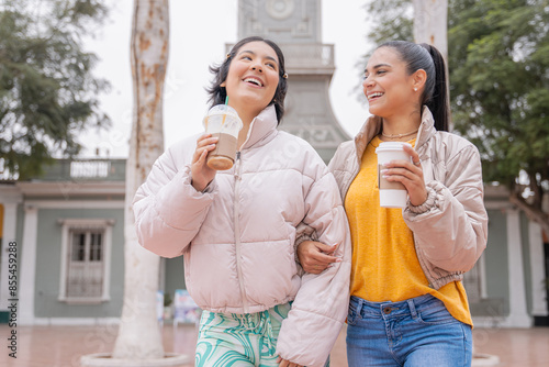 Friends drinking coffee and chatting walking the city