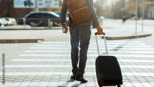 Cropped of black businessman crossing road with suitcase and backpack on his shoulder, catching taxi