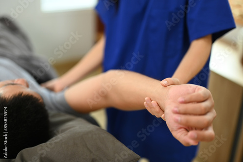 Close up physiatrist examining male patient frozen shoulder symptoms in a rehabilitation clinic