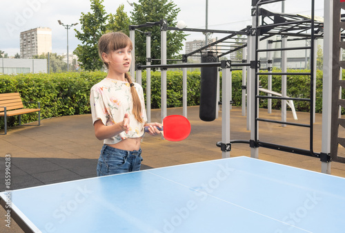 Cute girl playing ping-pong outdoors