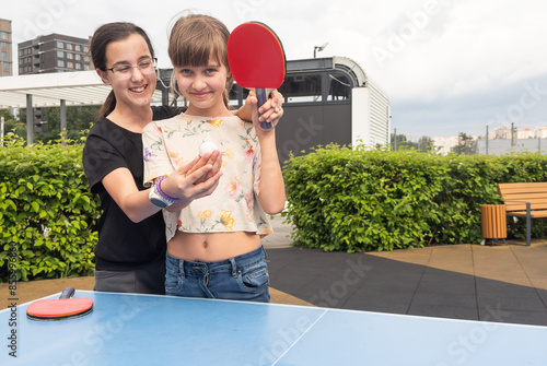 Happy girl friends playing ping pong table tennis, having fun together