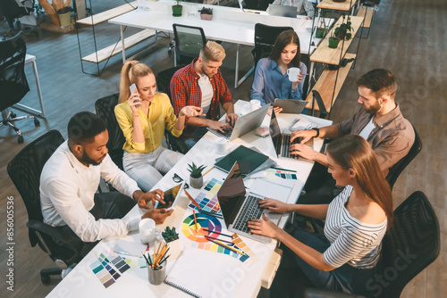 Several individuals sitting around a table, focused on their laptops, engaged in work or collaboration.