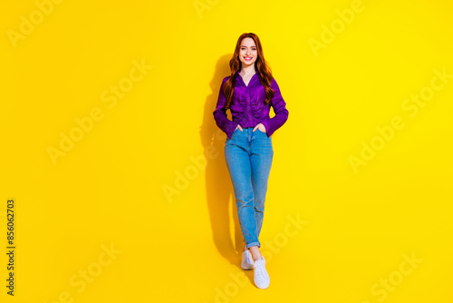 Full body length photo of sweet young woman wearing stylish purple satin shirt and jeans posing candid isolated on yellow color background