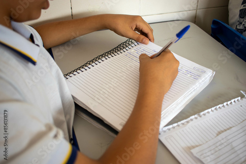 Estudante escrevendo em seu caderno na sala de aula