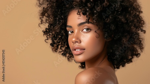 beauty portrait of a young woman with healthy curly hair and natural skin without makeup, on a beige background, skin and curly hair care concept