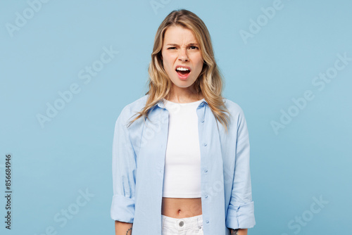 Young sad shocked surprised dissatisfied mad angry woman she wears white top shirt casual clothes looking camera isolated on plain pastel light blue cyan background studio portrait. Lifestyle concept.