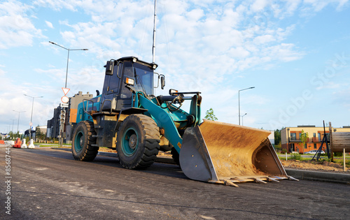 Wheel loader with a bucket on the road construction. Construction site with heavy machinery on road construction. Civil engineering. Heavy machinery for loading and unloading works on roadworks.