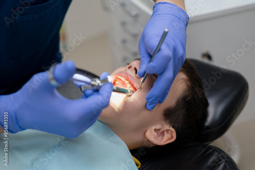 The dentist gives an anesthetic injection into the gum to a boy who is sitting in a dental chair. Dental treatment.