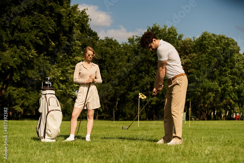 A young couple in elegant attire enjoys a game of golf on a lush green field at a prestigious club, embodying the epitome of upper-class leisure.