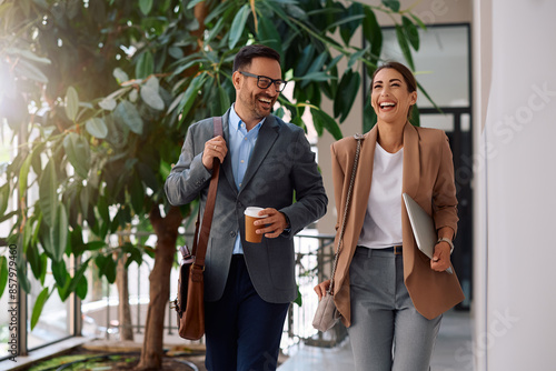 Cheerful coworkers talking while walking through office hallway.