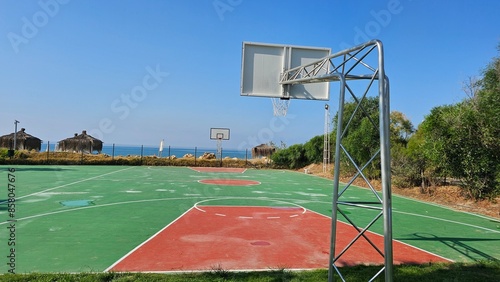 An empty basketball court, in the early sunny morning outdoors, by the sea