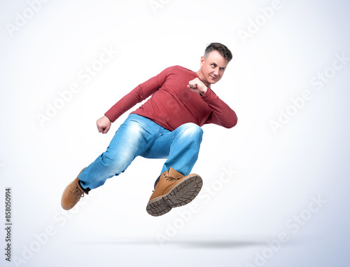 Full length handsome man in casual clothes runs quickly jumping high, isolated on a light blue background. Funny man joyful running in copy space. 