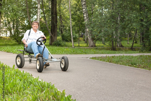 An elderly woman rides a toy car.