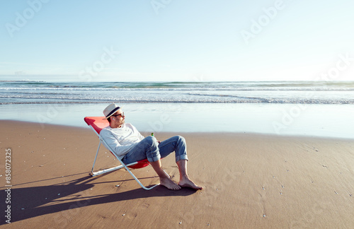 alone mature man lying on beach chair relaxing looking the horizon on the remote beach shore