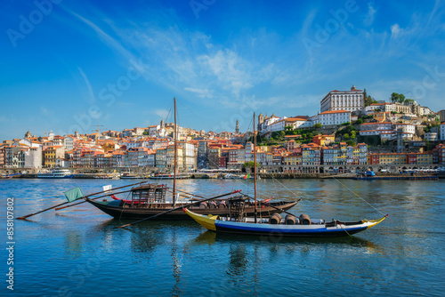 View of Porto city and Douro river with traditional boats with port wine barrels from famous tourist viewpoint Marginal de Gaia riverfront. Porto, Vila Nova de Gaia, Portugal