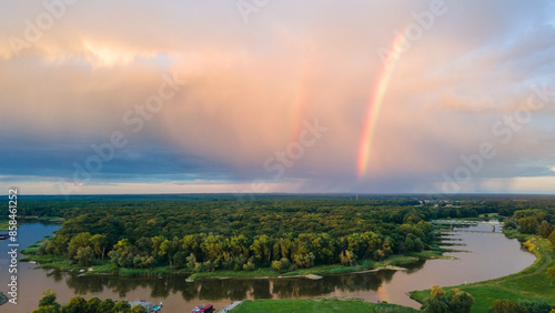 Widok z lotu ptaka na miasto z tęczą nad miastem i lasem wieczorem 