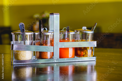 Condiment set of sugar, chilly flakes, chilli vinegar and fish sauce mixed chilli in glass cruet on wooden table in resturant. For seasoning noodle.