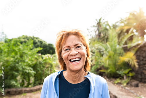 Happy senior Latin woman smiling into the camera while walking in a public park