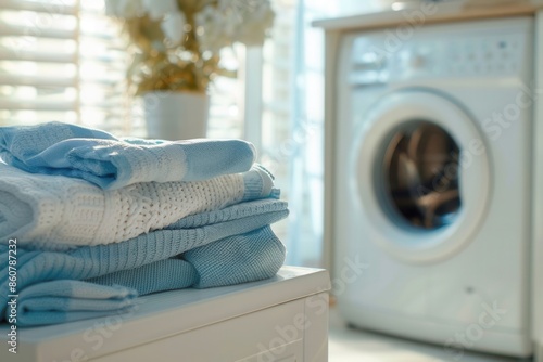 A stack of freshly washed and folded laundry sits on a white countertop next to a washing machine in a home laundry room. Generative AI