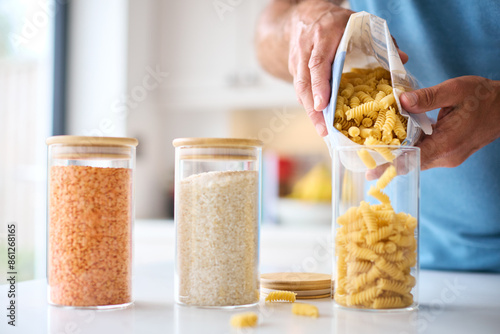 Close Up Of Man Filling Up Storage Jar From Bag In Kitchen At Home