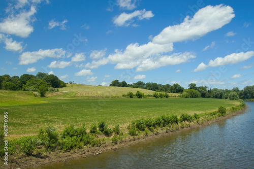 Sunny Summer landscape view of the Missouri River flowing by lush, hilly green farmland along the Katy Trail, near Jefferson City, Missouri.