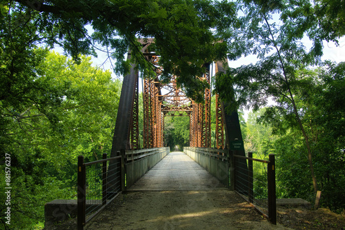 Summer landscape of the Katy Trail passing over an old railroad trestle in a lush green forest, near Sedalia, Missouri.