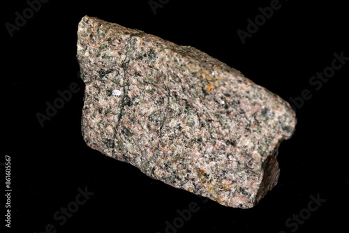 A sample of Archean aged pink and green coloured alkaline granite against a black background