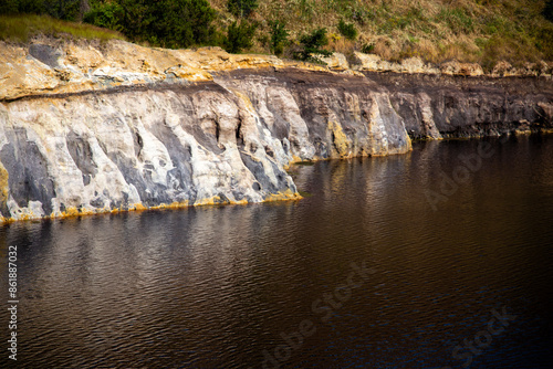 View of the jagged rock face with mineral residues at the edge of the lake, Solfatara locality, Pomezia, Rome, Italy