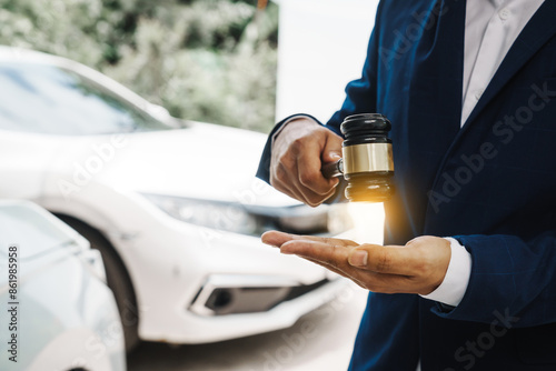 businessman in a suit and a lawyer, holding a wooden gavel, stand in front of a car, discussing legal aspects like citations, liability, and negligence related to a traffic violation...