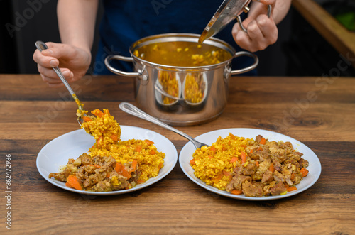 Pora obiadowa, żona nakłada na talerze obiad z garnka, ryż z kurczakiem w sosie curry