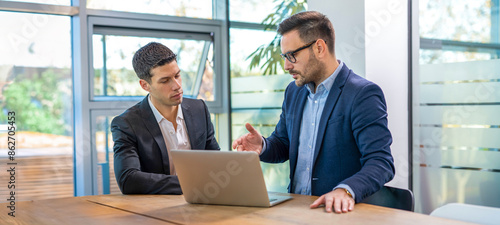 Businessman explaining something to a colleague using a laptop at office.