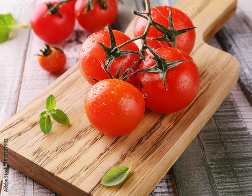 Red ripe tomatoes on the vine ona wooden cutting board on a table