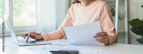 Deduction planning, debt asian young woman hand using calculator to calculating money balance from bill and income, cost budget expenses for pay money form personal individual on table at home.