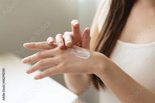Health skin care, beauty smile asian young woman, girl hand applying, putting moisturizer on her arm, shoulder after shower bath at home. Skin body cream moisturizing lotion, routine in the morning.